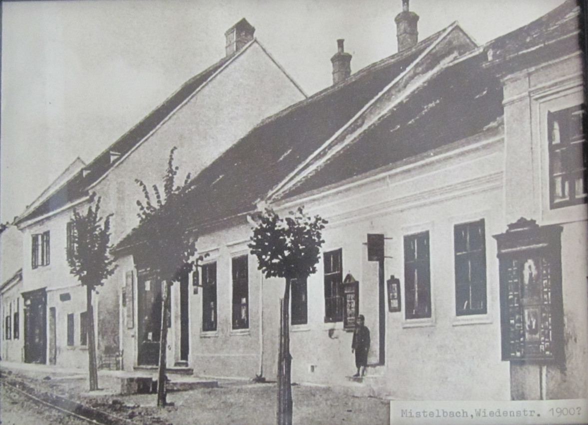 Das Haus Wiedenstraße Nr. 6 zu Beginn des 20. Jahrhunderts. Möglicherweise handelt es sich bei dem Kind um Leopold Forstner jun., der vor seinem Elternhaus posiert. Hinweis auf das hier ansässige Fotoatelier sind auch die Fotokästen, die auch an der Ecke zum Nachbarhaus angebracht sind.